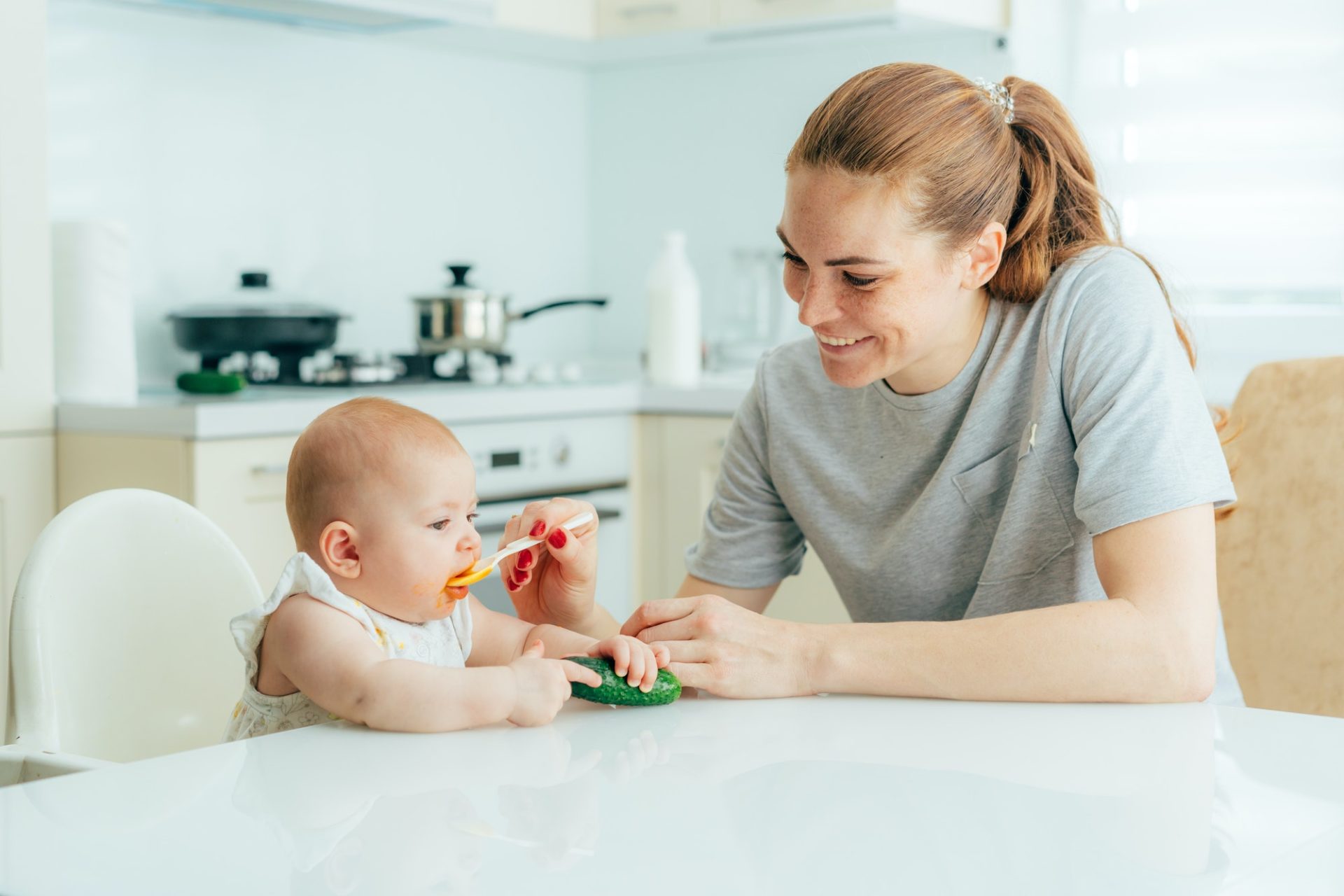 happy-smiling-redhead-mom-feeds-her-baby-with-vegetable-puree-in-the-kitchen-at-home--e1634610116620.jpg